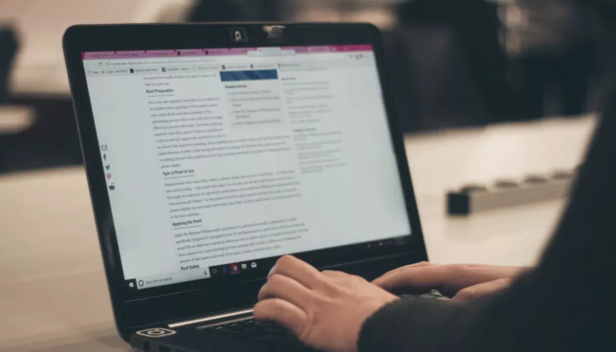 A person typing on a laptop displaying a blog article.