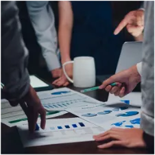 Several people gathered around a table examining documents.,