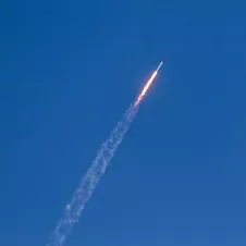 A rocket launching into a clear blue sky, symbolizing growth, progress, and long-term success.