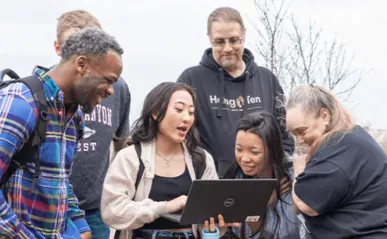 6 people gathering around a laptop.