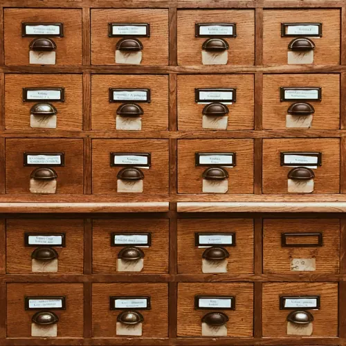 A vintage wooden filing cabinet with labeled drawers, representing organization, categorization, and efficient information management.