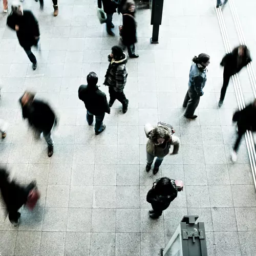 A high-angle view of people walking in a busy public space, symbolizing corporate environments and large-scale commerce.
